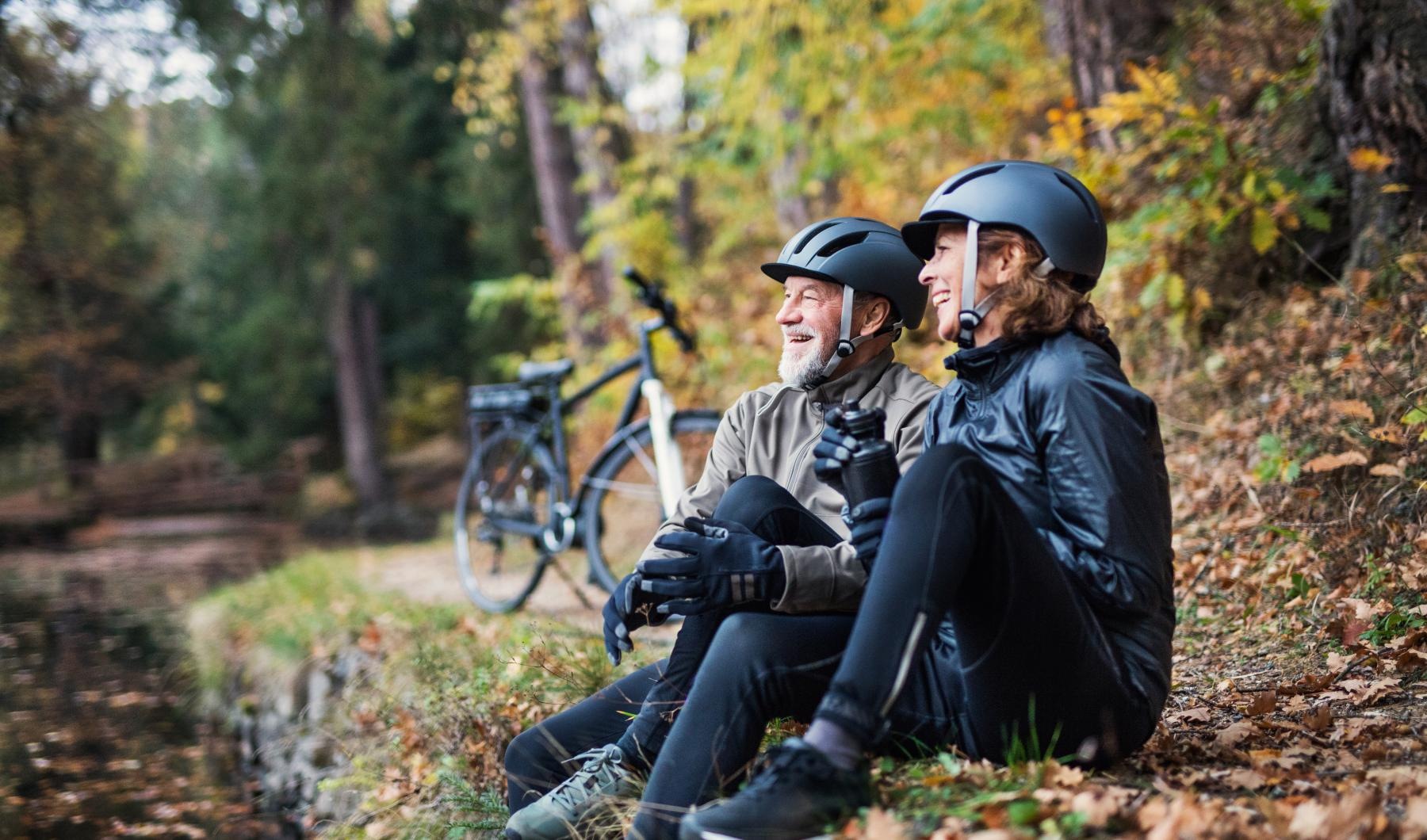a man and woman sitting on a trail with a bicycle