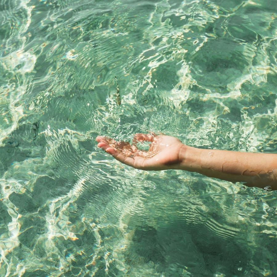 a person's hand and arm in the water